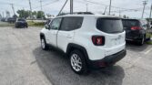 White Jeep SUV in a dealership lot with other cars and power lines overhead