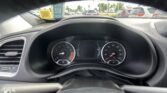 Driver’s-eye view of the dashboard and steering wheel, looking through the windshield at a parking lot with cars ahead on both sides