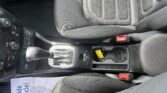 View of the car's center console: gear shifter, climate controls, and a cup holder with a yellow tag inside the opening.