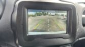 In-dash rearview camera display showing parking guidance lines and a street behind the car, with a 'Check entire surroundings' message.