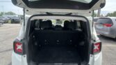 Open hatch of a white SUV showing the cargo area with folded third-row seats and surrounding parking lot vehicles