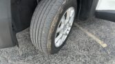 Close-up of a car tire and alloy wheel in the wheel well, with dirt and grime on the tire sides.
