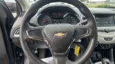 Driver’s view of a Chevrolet interior: steering wheel with the gold bowtie emblem and the instrument cluster ahead, plus the center touchscreen to the right.