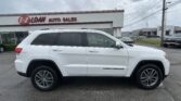 White Jeep Grand Cherokee in the foreground at E-Z Loan Auto Sales dealership with a red sign above.