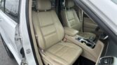 Interior of a beige leather SUV showing front seats, center console, and open driver-side door with dashboard partially visible