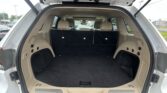 Open SUV cargo area with beige interior, showing folded third-row seats and wide storage space behind the rear bumper.