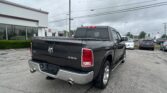 Black Ram pickup truck in a car dealership lot, rear view showing 4x4 badge and dual exhausts with Toyota signs in the background.