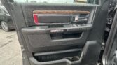 Driver's side interior door panel of a RAM truck with wood trim, chrome handle, and window controls in view