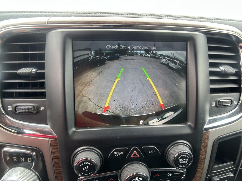 Infotainment screen showing rearview camera with parking guideline lines and the message 'Check Entire Surroundings'.