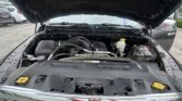 Open hood of a black pickup revealing the engine bay with hoses, the air intake, and a battery on the right side