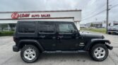 Black Jeep Wrangler SUV parked in front of E-Z Loan Auto Sales dealership.