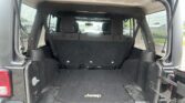 Open rear of a Jeep showing the cargo area with back seats upright and a black floor mat bearing the Jeep logo