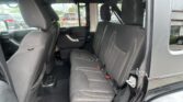 Back seat area of a black SUV with three seat cushions and headrests, visible seat belts, and doorway frame on the right.