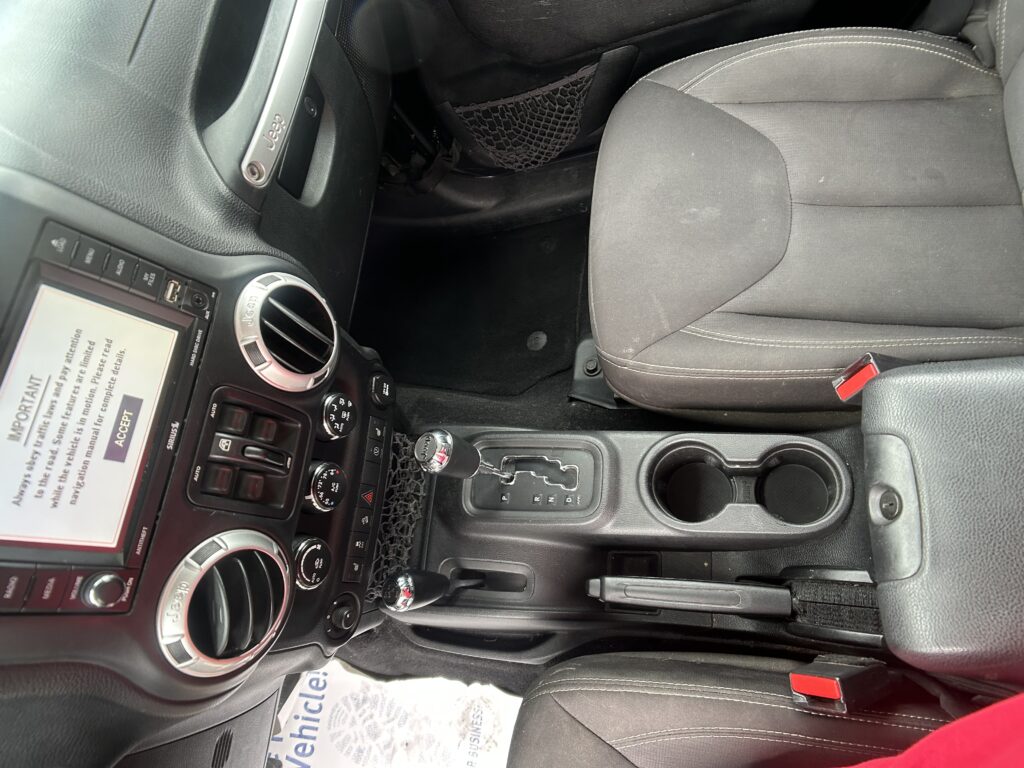 Jeep car interior with center console, touchscreen display, circular air vents, and gear shift visible between front seats.