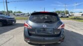 Rear view of a gray Nissan Murano SL AWD in a parking lot with other cars and a dealership building in the background