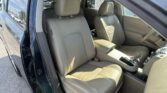 Open car door view of a beige leather sedan interior, front seats and center console visible.