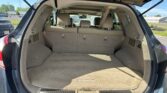 Cargo area of a beige SUV with rear seats upright and the hatch open, showing a roomy trunk and folded third-row headrests (Nissan Murano).