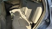 Rear interior of a beige leather SUV, three-seat bench with headrests, door panel visible, parked cars outside the window.