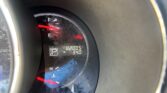 Close-up of a car instrument cluster showing a low fuel level, with a red warning light on and the odometer reading 82,005 miles (partial display).