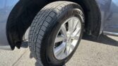 Close-up of a car tire mounted on a silver alloy wheel inside a blue vehicle's wheel well.