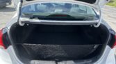 Open trunk of a white hatchback showing a black cargo area with a mesh floor and rear seats visible behind