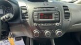 Interior of a car dashboard with the center console radio showing 96.9 FM, red display, and climate control knobs below; steering wheel on the left and sunny windshield view ahead.