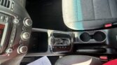 Interior of a car's front cabin showing the center console, gear shifter, climate controls, cup holders, and gray fabric seats.