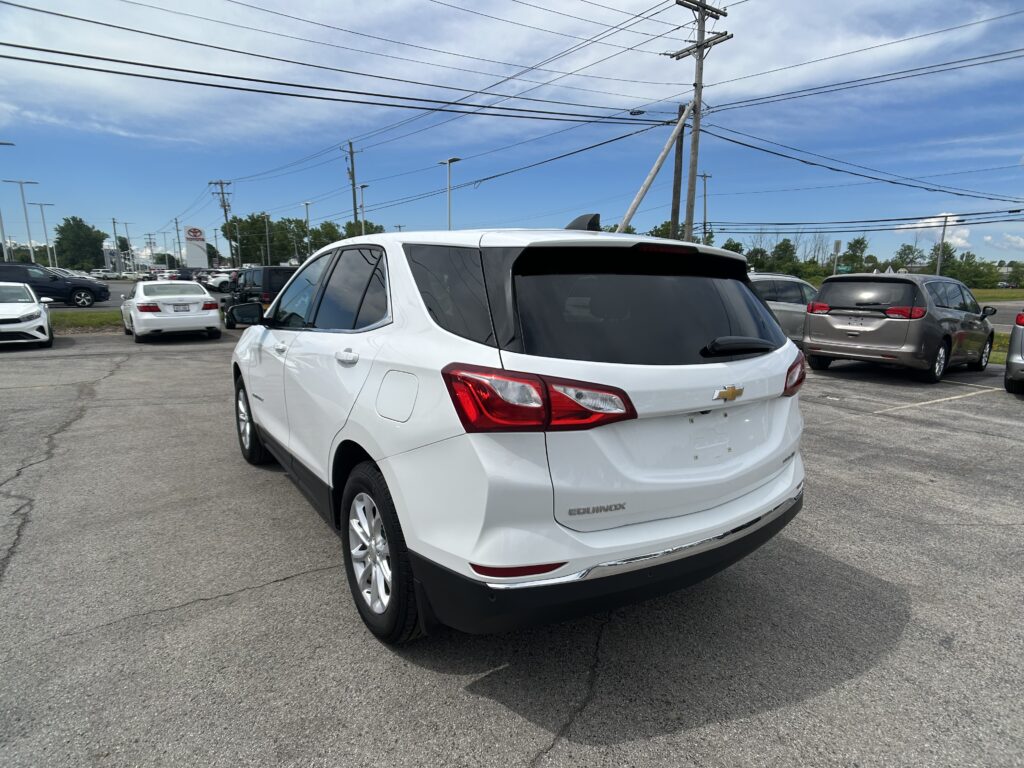 White Chevrolet Equinox SUV parked in a car lot with other vehicles and power lines overhead.