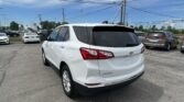 White Chevrolet Equinox SUV parked in a car lot with other vehicles and power lines overhead.