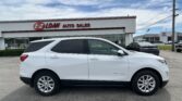 White SUV parked in front of an auto dealership with a sign reading 'E-Z LOAN AUTO SALES' under a blue sky.