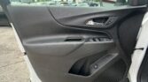 Close-up of a car's black interior door panel with a silver handle and window controls; a parking lot is visible through the window.
