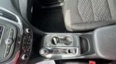 Interior of a car focusing on the center console: gear shifter, cupholders, and front passenger seat with textured fabric upholstery.