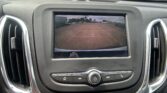 Car dashboard with a rearview camera screen showing parking guide lines in a parking lot.