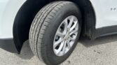 Close-up of a car tire and silver alloy wheel mounted on a white SUV, showing the wheel arch and fender.