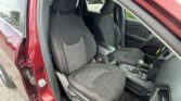 Front seats of a red car, black fabric upholstery with contrast stitching, center console and gear shifter visible.