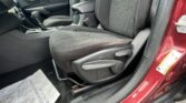Interior of a car showing front driver and passenger seats with black fabric upholstery and white stitching, center console and gear shifter visible, red door frame nearby.