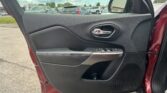 Interior of a car door panel with window control buttons and a chrome door handle, view of a parking lot outside the window.