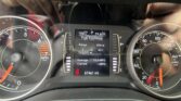 Close-up of a car instrument cluster with a center digital display showing Fuel Economy and range alongside analog tachometer and speedometer edges.