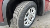 Close-up of a car tire mounted on a silver wheel in the front wheel well of a red vehicle.