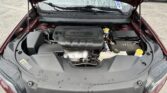 Open hood of a red car showing the engine bay and wipers, with fluid reservoirs visible in the foreground.