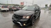 Black Dodge SUV in the foreground on a rainy dealership lot, with minivans parked in the background and an E-Z Loan Auto Sales sign visible in the distance.