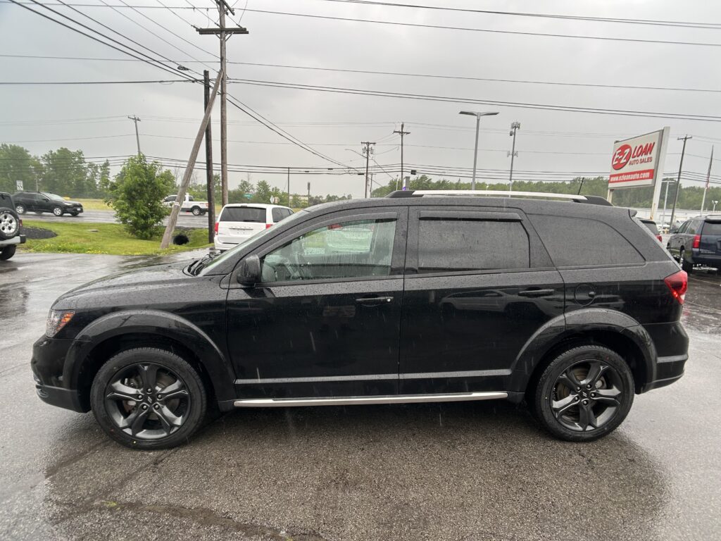 Black SUV parked in a rain-soaked lot with a red EZ Loan sign in the background.