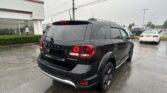 Rear three-quarter view of a black Dodge Durango SUV in a wet parking lot on a rainy day, taillights glowing red.
