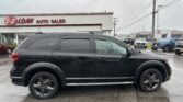 Black SUV in the foreground at an auto dealership, with an E-Z Loan Auto Sales sign and other vehicles in the lot on a rainy day.