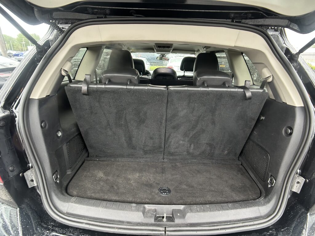 Interior of an SUV with folded-down cargo space behind the rear seats; view from the open tailgate showing black carpeting and rear seatbacks ready for cargo.