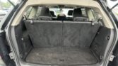 Interior of an SUV with folded-down cargo space behind the rear seats; view from the open tailgate showing black carpeting and rear seatbacks ready for cargo.