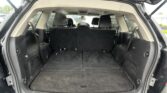 Open rear hatch of a black SUV showing an empty cargo area with folded third-row seats and dark carpeting