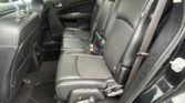 Interior of a black leather SUV rear seat row with three seats, headrests, and visible seat belts behind the front seats.