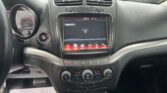 Center console car interior with touchscreen display, climate knobs, and start button; paper sign on floor reads 'We Take Pride In Your Vehicle!'