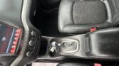 Center console area with gear shifter and black leather seat in a car interior.